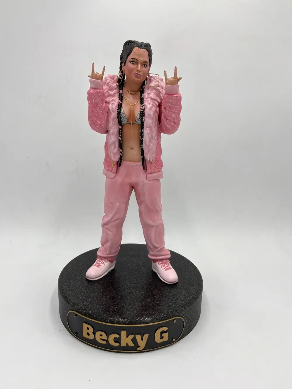 Figura de la cantante Becky G con chaqueta rosa sobre una peana negra con su nombre
