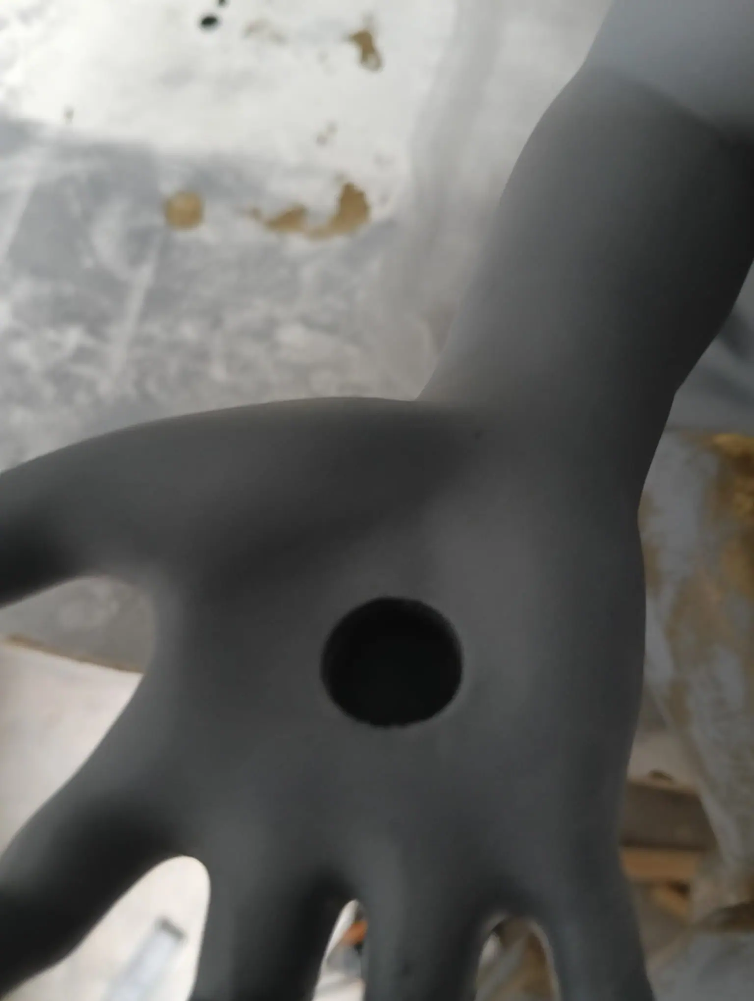 Una de las manos del cupido en resina gris, antes de pintar, con un encaje redondo