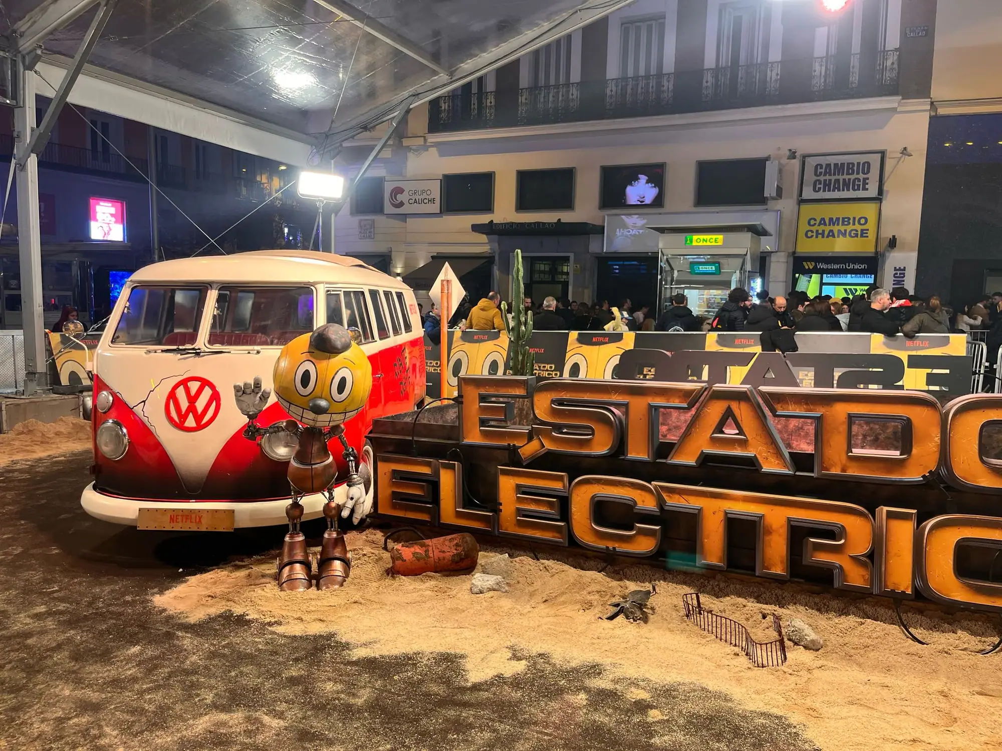 Escenografía del estreno de Estado eléctrico para Netflix, con una furgoneta antigua, el muñeco Cosmo y el título en volumen