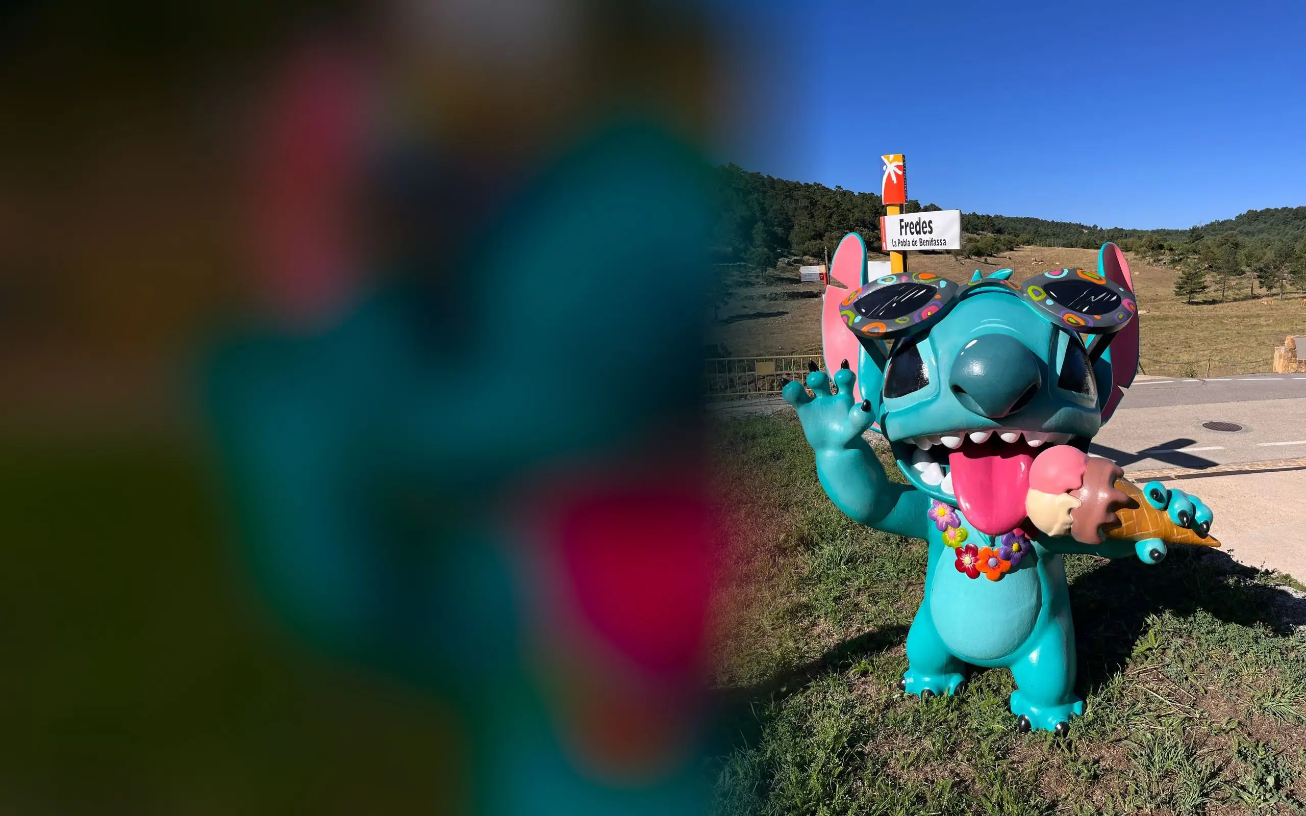 Figura de fibra de vidrio de un personaje azul con gafas de sol, instalada al aire libre en la montaña