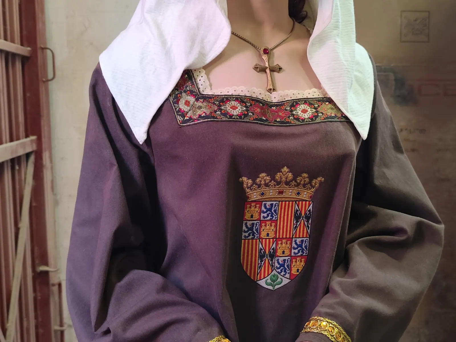 Detalle del pecho con el escudo de Castilla y Aragón, la cruz al cuello y el bordado del escote