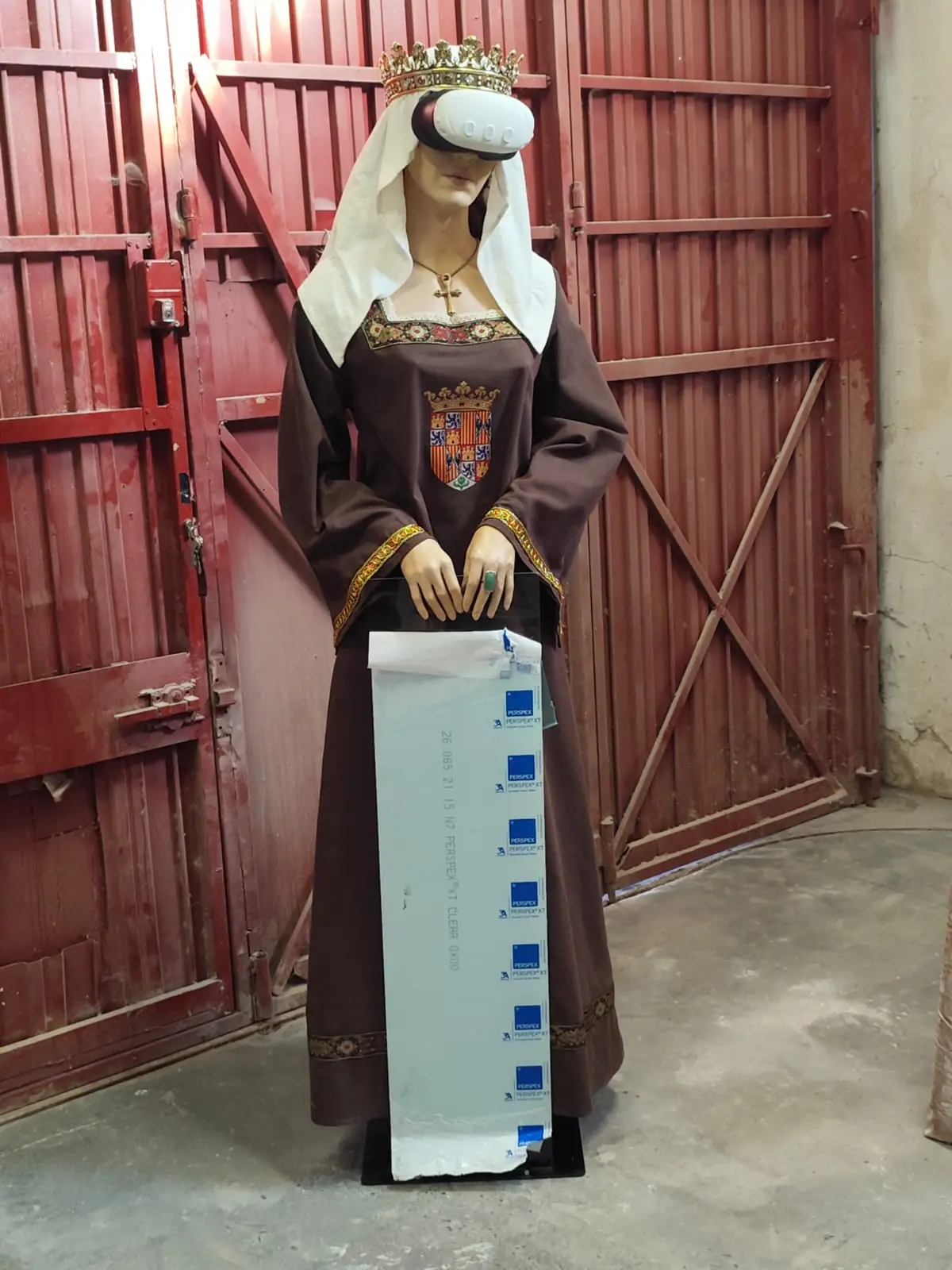 Escultura de Isabel la Católica a tamaño real, de frente, con toca blanca, corona y gafas de realidad virtual