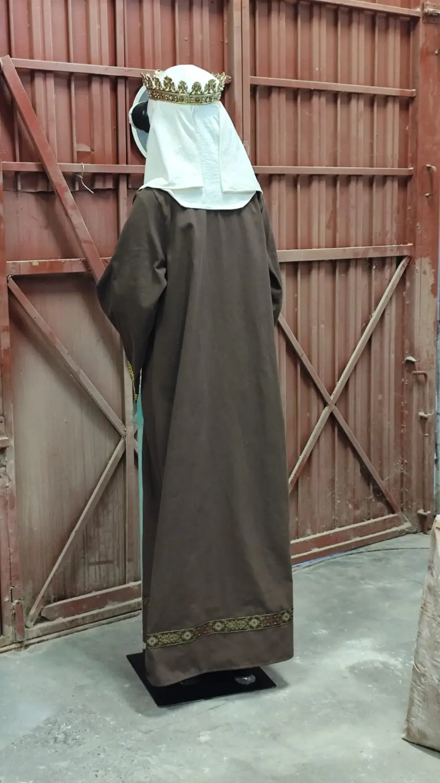 La figura de espaldas, con la toca blanca y el vestido marrón hasta el suelo