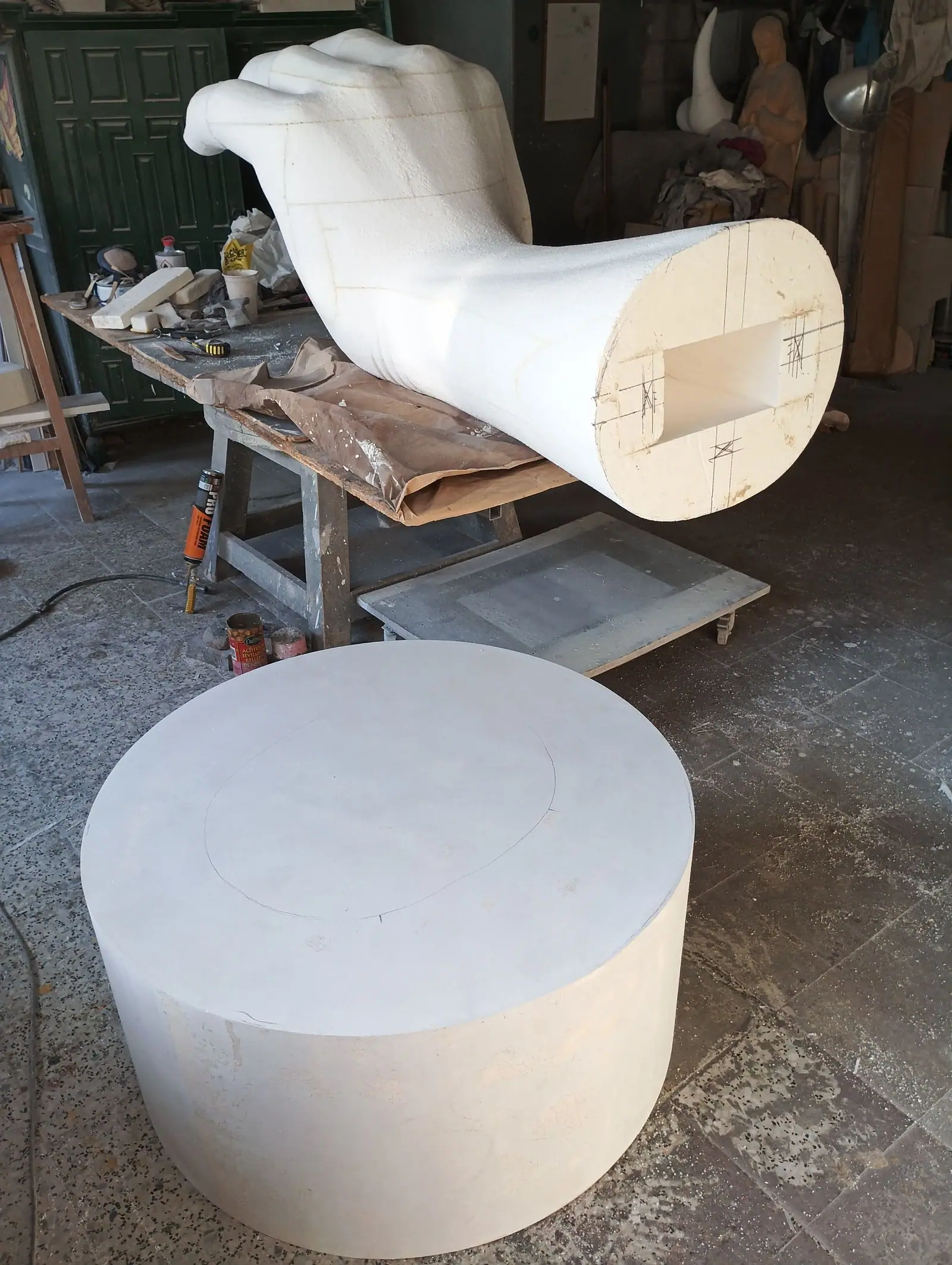 La mano separada del brazo, tumbada sobre la mesa, con la pieza de madera de la unión a la vista y la peana al lado