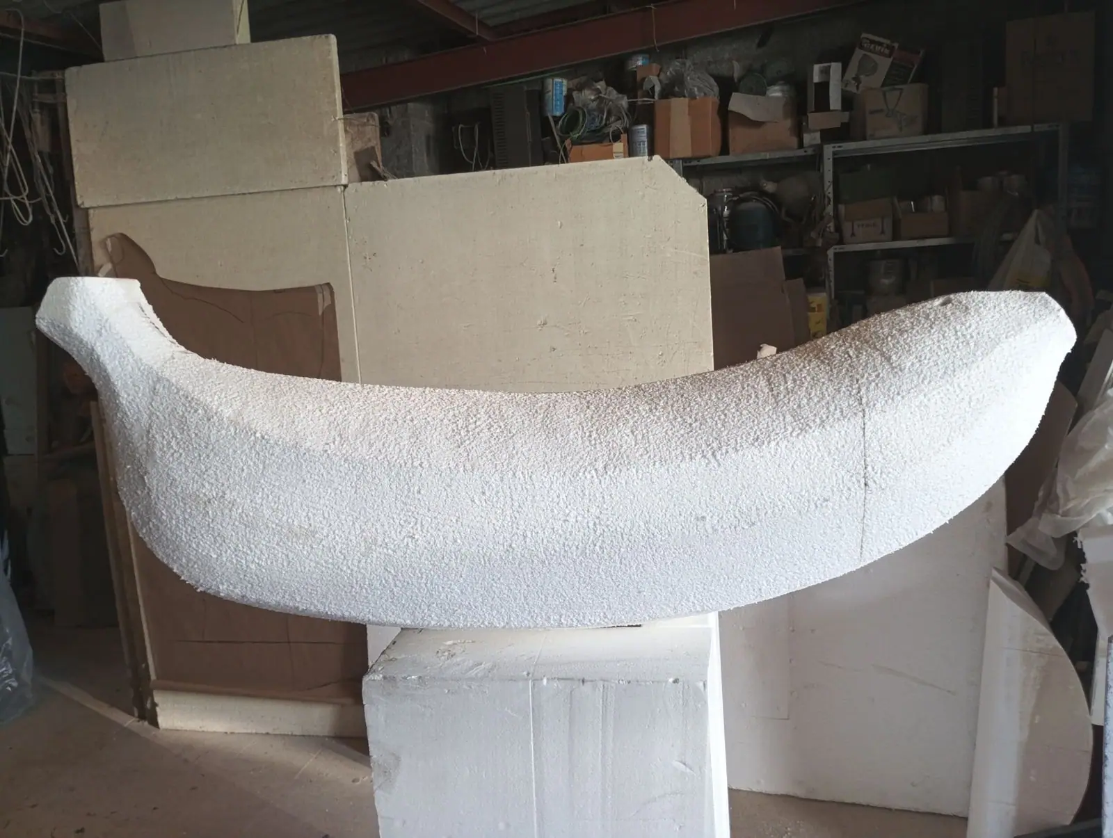 El plátano tallado en poliespán blanco, apoyado sobre un bloque en el taller