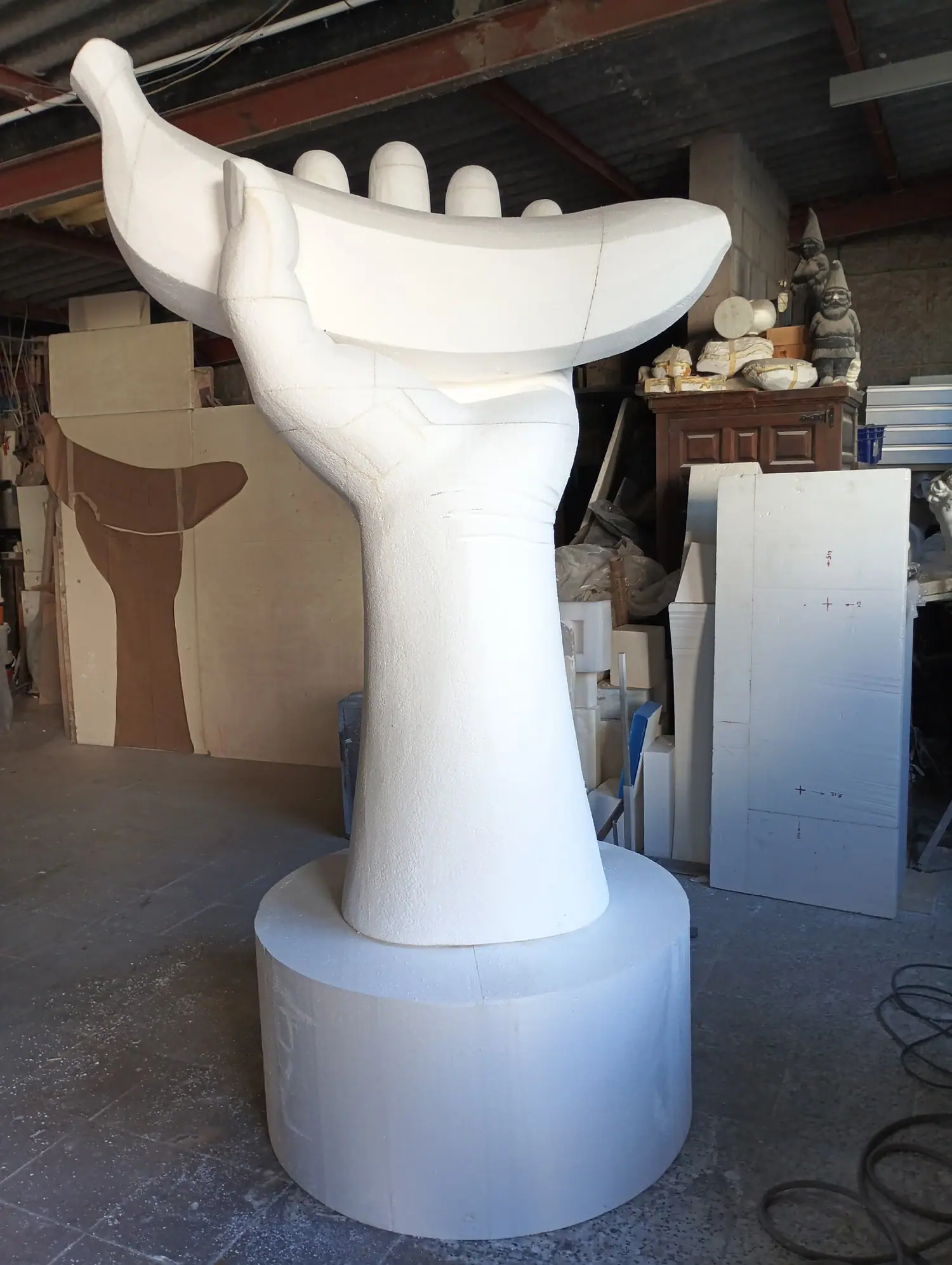 Mano gigante de poliespán sosteniendo un plátano, en bruto en el taller, antes del recubrimiento y la pintura