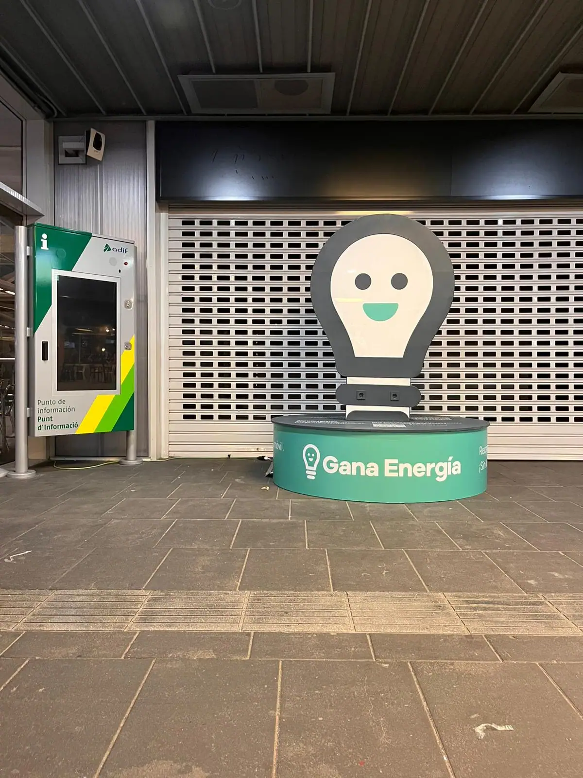 Corpóreo de una bombilla sonriente de Gana Energía sobre una peana verde en una estación