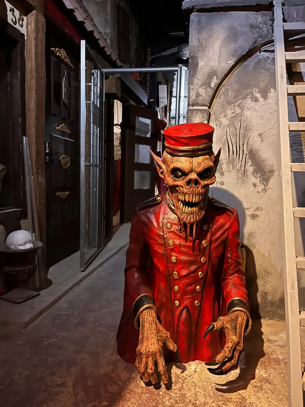 Figura de un botones con cara de calavera en un pasillo de puertas viejas de un escape room