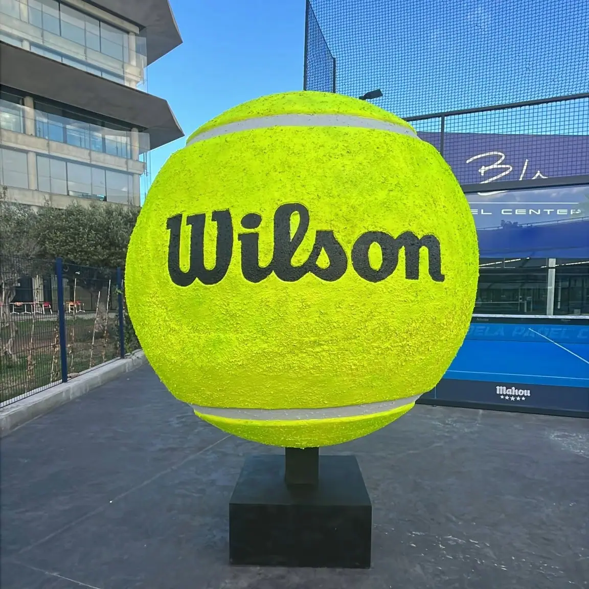Pelota de tenis gigante de fibra de vidrio con el logotipo de Wilson sobre su peana