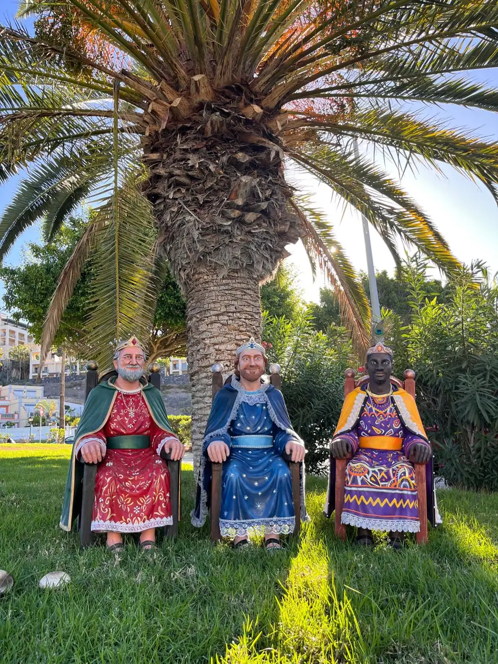 Los tres Reyes Magos a tamaño real, policromados y sentados en sus tronos bajo una palmera