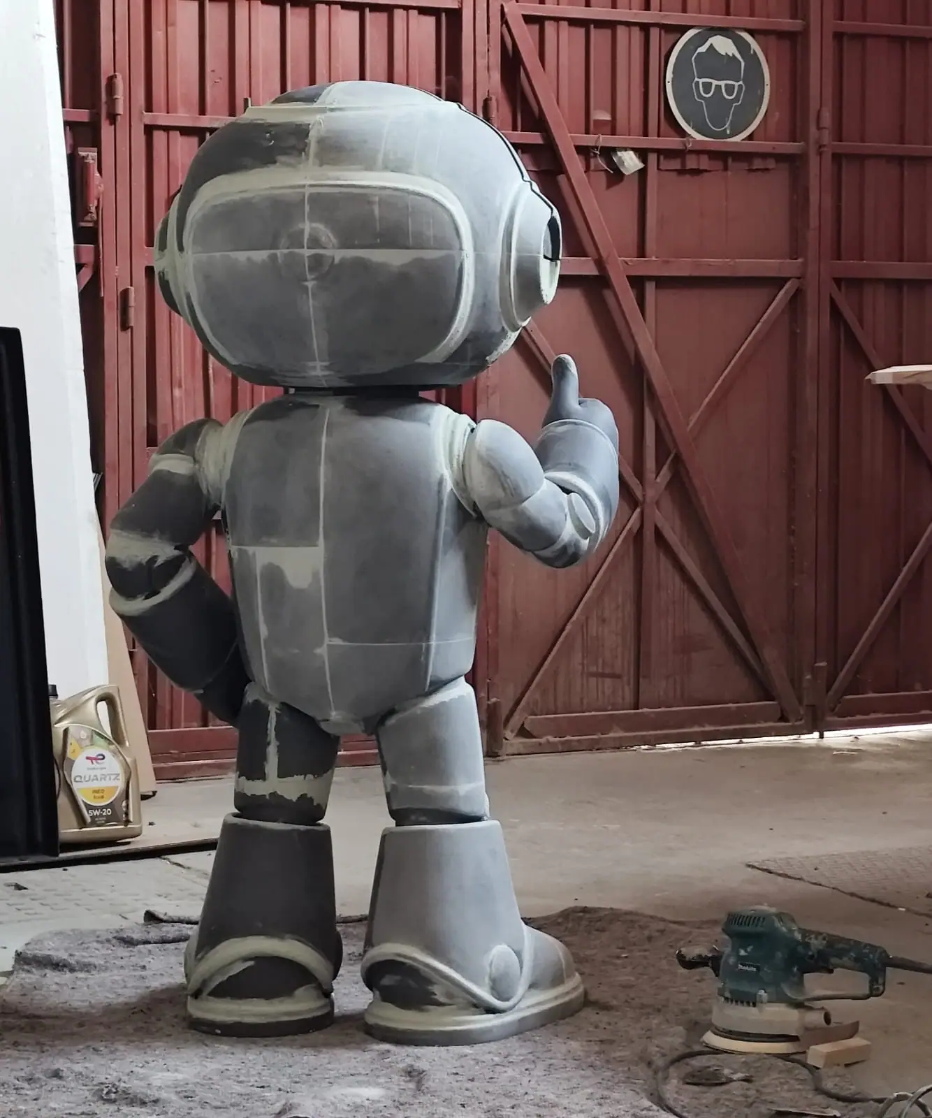 El robot montado entero, con las juntas rellenas y lijadas, junto a una lijadora