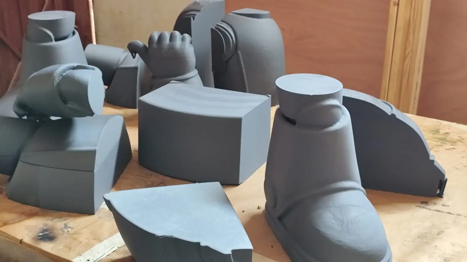 Botas, manos y piezas del cuerpo del robot fresadas en poliespán gris sobre la mesa del taller