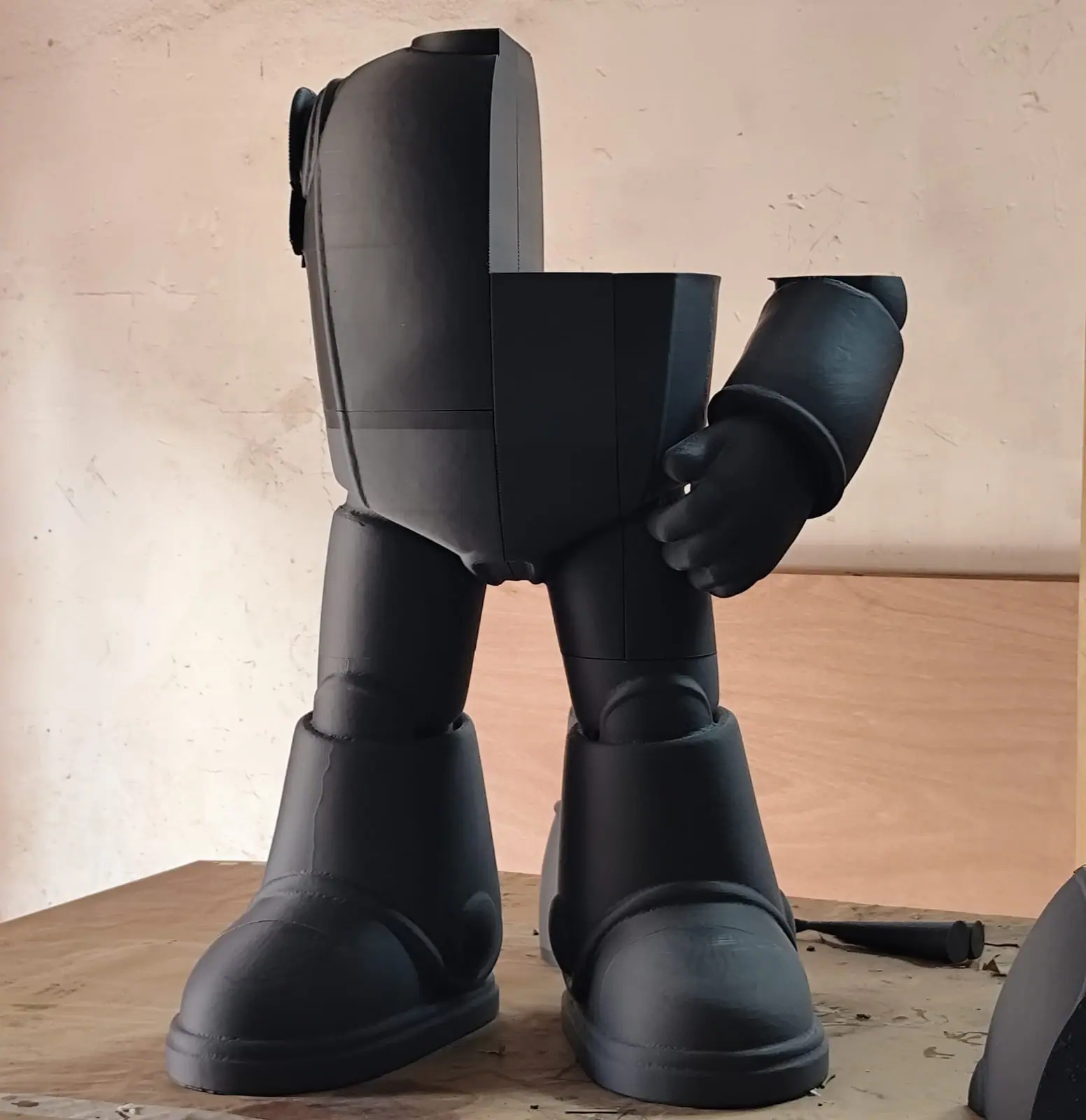 Piernas, botas y cuerpo del robot ya cubiertos de resina, en gris oscuro