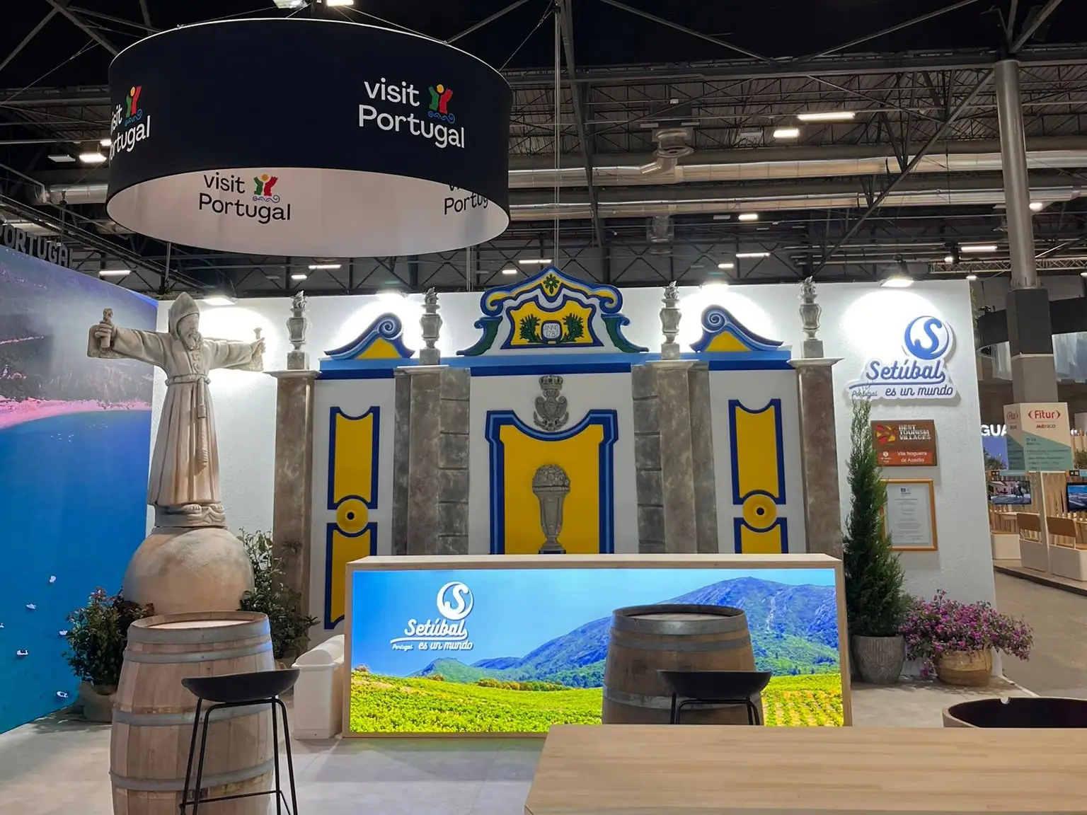 Stand de Visit Portugal en una feria, tematizado como un pueblo de Setúbal, con barricas y una escultura sobre una tinaja