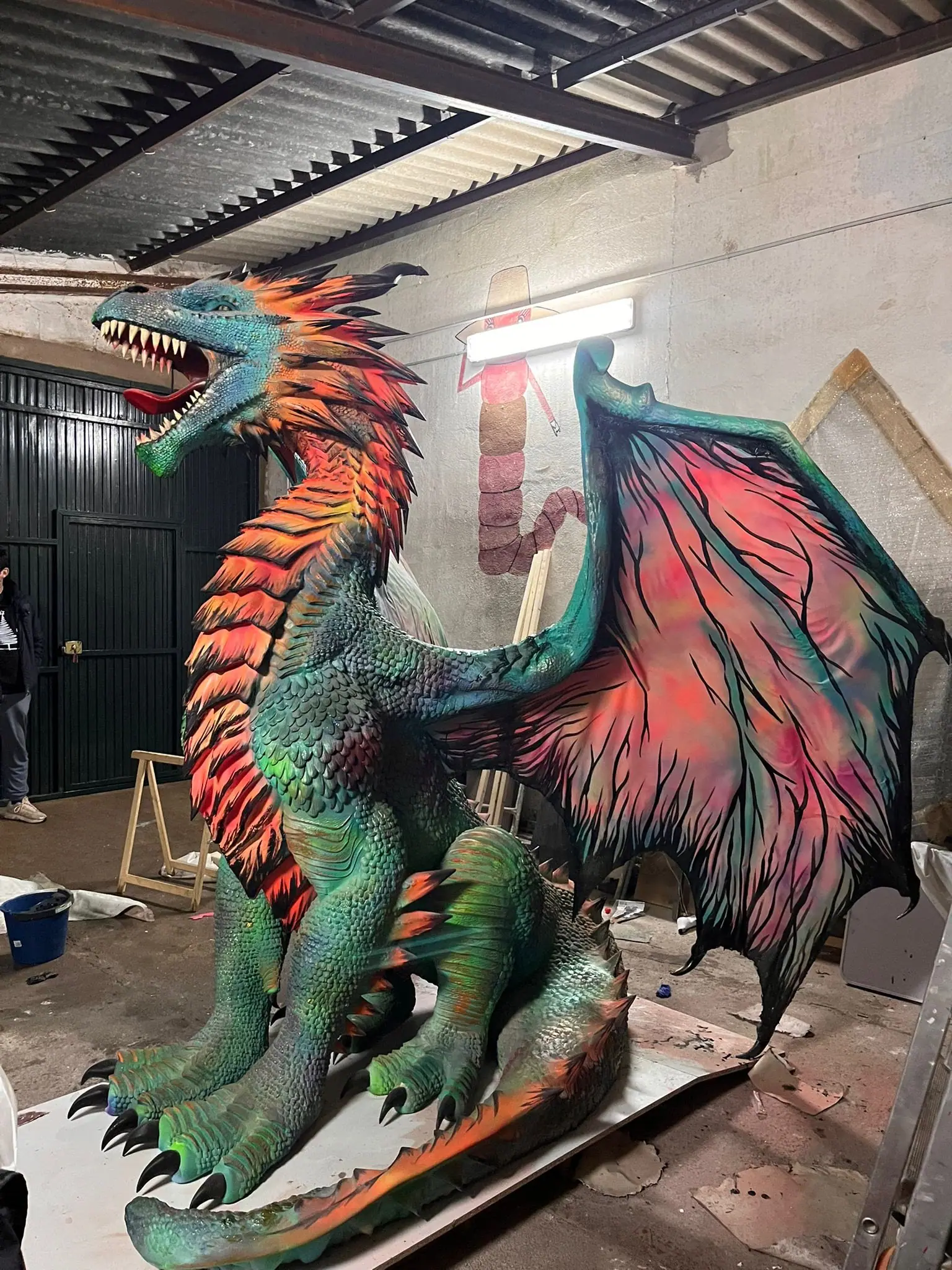 Dragón de poliespán con las alas abiertas pintado en verde, naranja y rojo