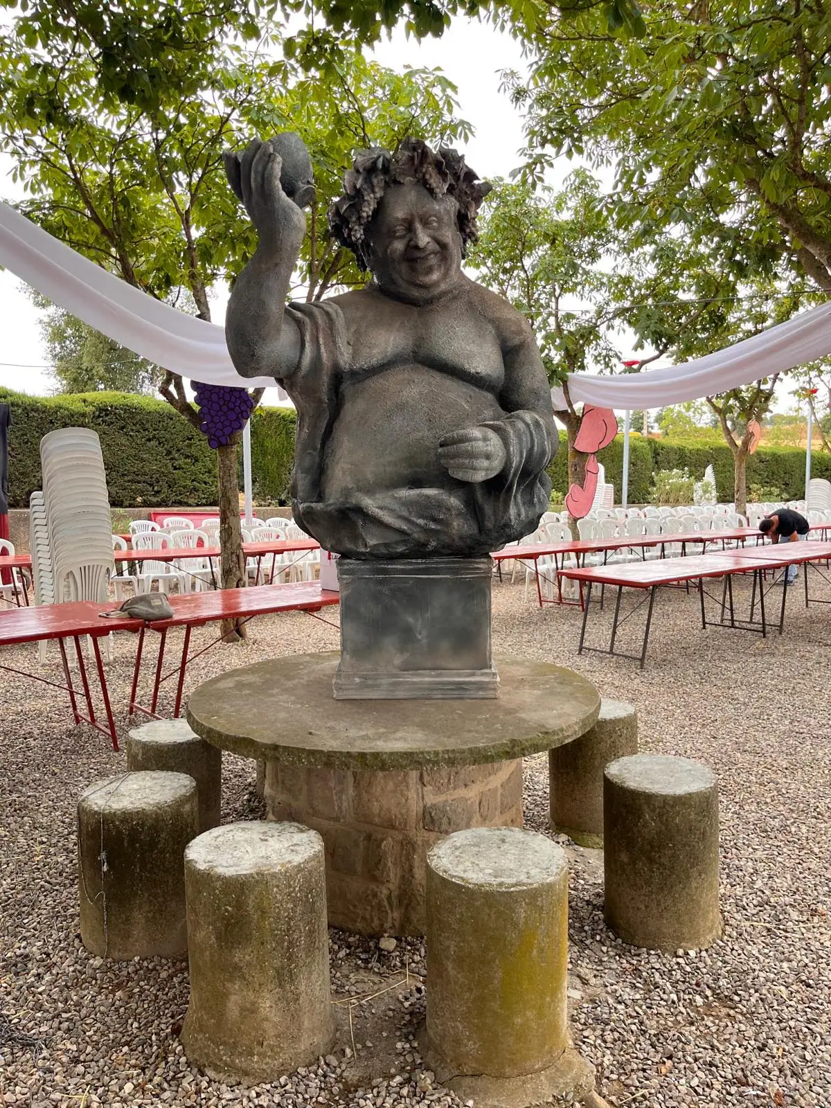 Escultura de fibra de vidrio de un personaje con una piedra en la mano, instalada en un jardín