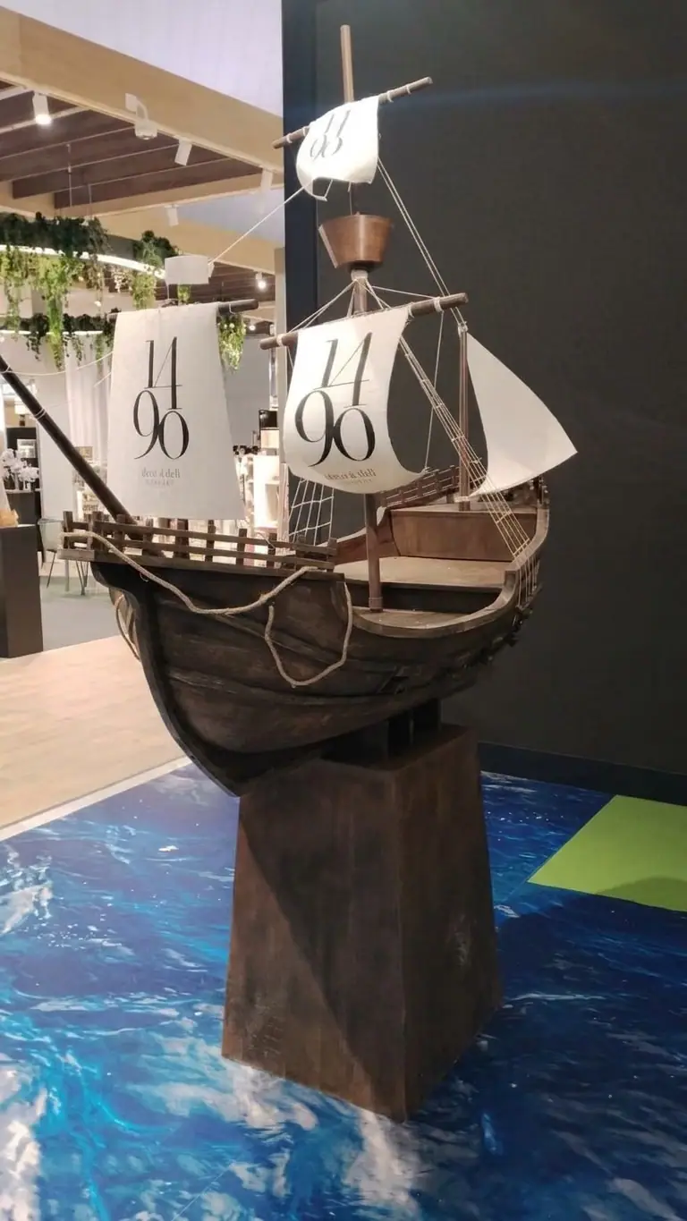 Barco corpóreo con velas de una marca, montado sobre una peana en un evento
