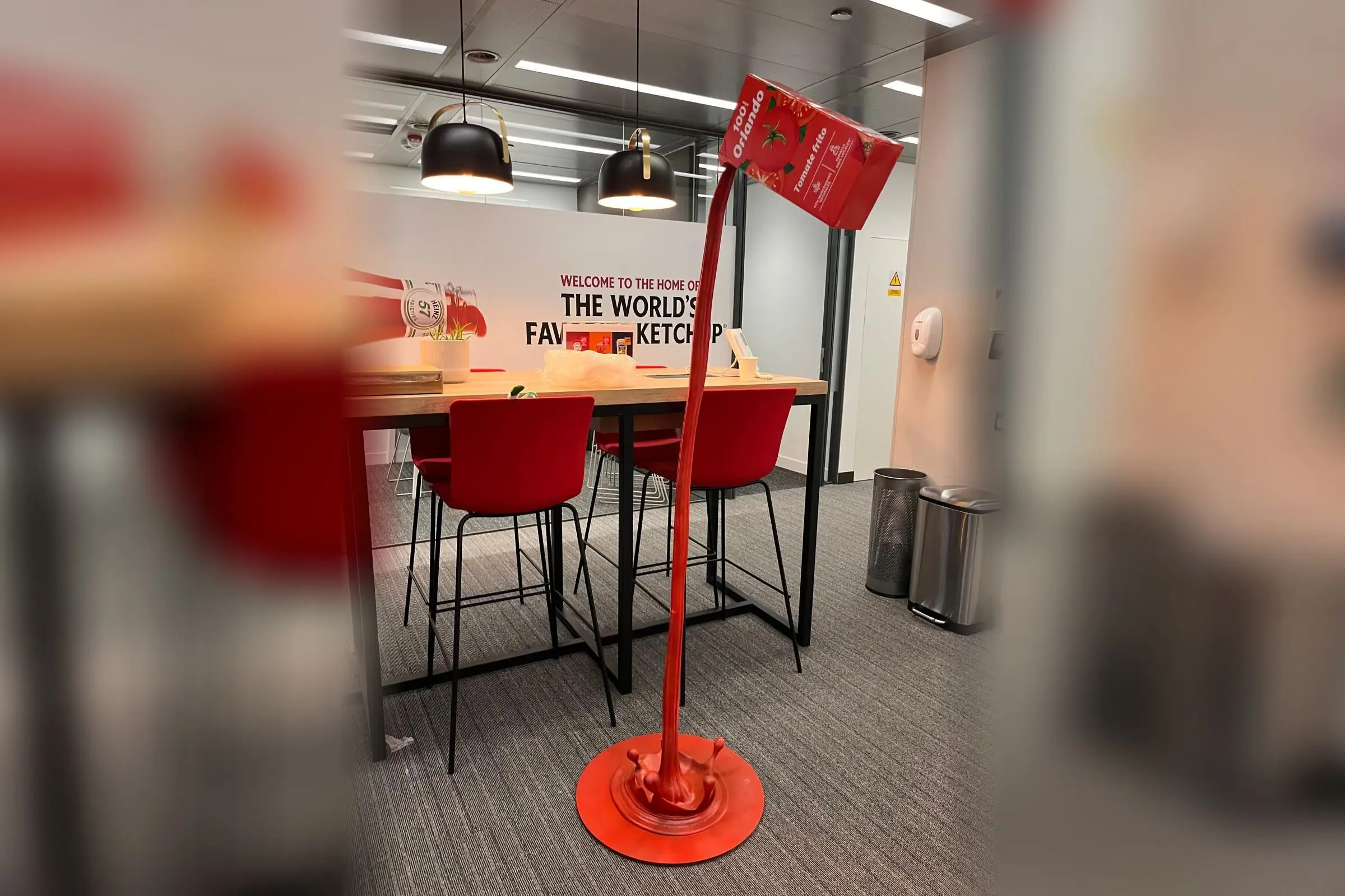 Réplica a gran escala de un brik de tomate frito Orlando vertiendo un chorro de tomate